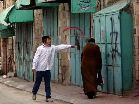 Settler throws wine on a Palestinian woman (Photo: Rina Castelnuovo)