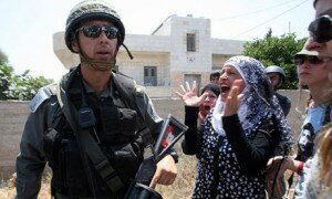 A Palestinian woman shouts at an Israeli soldier as clashes erupted with Palestinian protesters on Friday during a demonstration against the expansion of the Israeli settlements at Nabi Salih village near the West Bank City of Ramallah. [Photo: Alaa Badarneh/EPA]